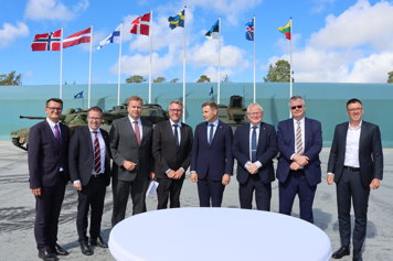 The Nordic and Baltic defence ministers are standing outside the Gotland Regiment base P 18. 