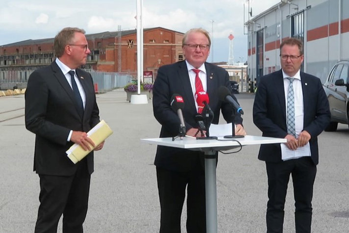 The three ministers standing in Malmö Port in front of microphones.