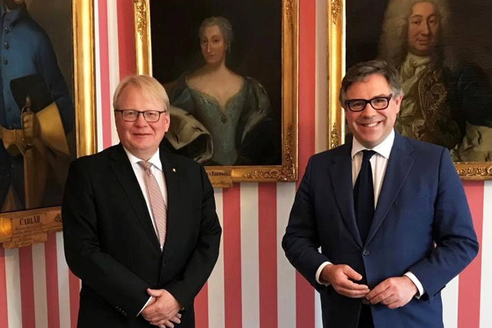 Peter Hultqvist and Jeremy Quin in suits with paintings in the background.