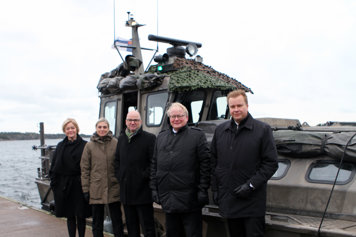 The participating ministers standing outside in front of a ship.