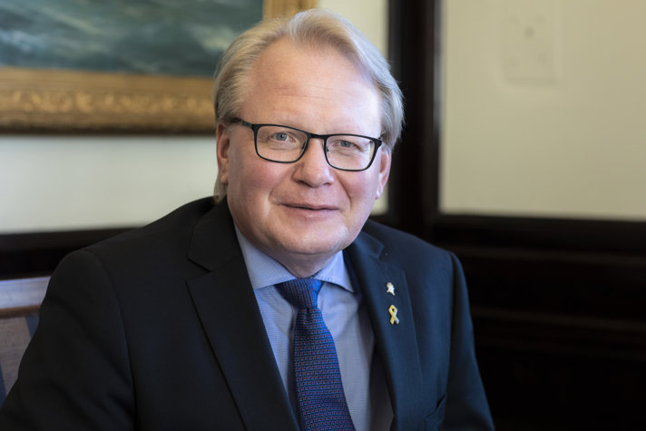 Peter Hultqvist in a suit sitting on sofa inside.