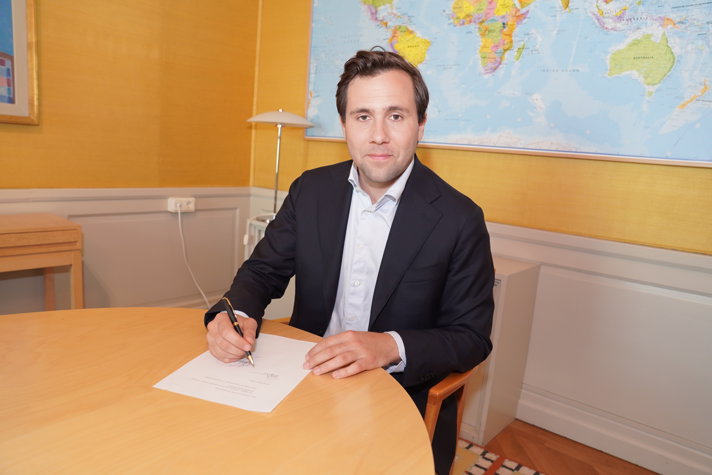 Minister for International Development Cooperation and Foreign Trade Benjamin Dousa signing document.