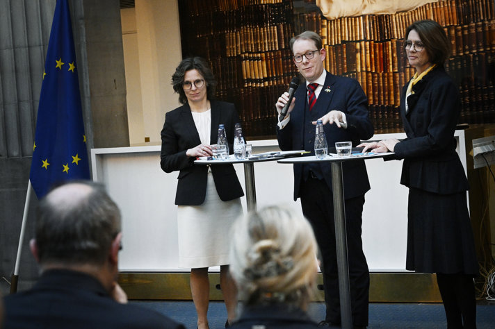 Billström and Roswall standing at  a podium speakaing to the audience