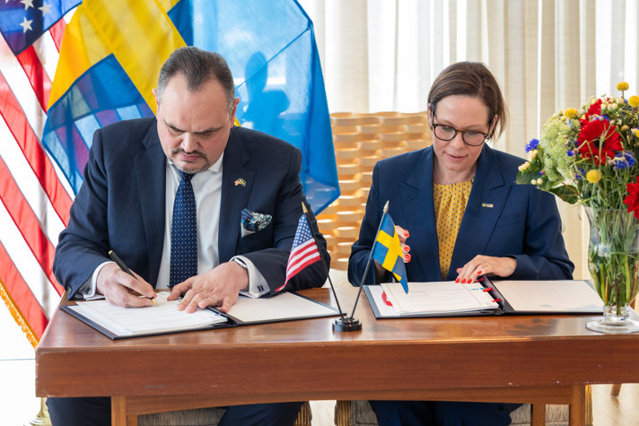 Maria Malmer Stenergard sits at a table and signs an agreement with the US.